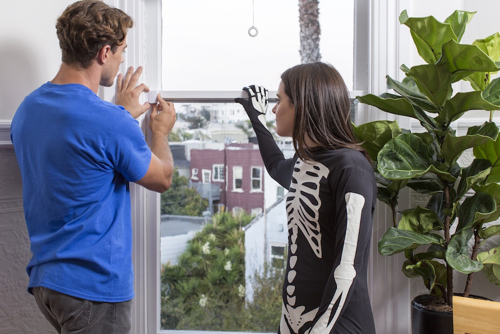 man and woman installing samsung smart things sensor on window