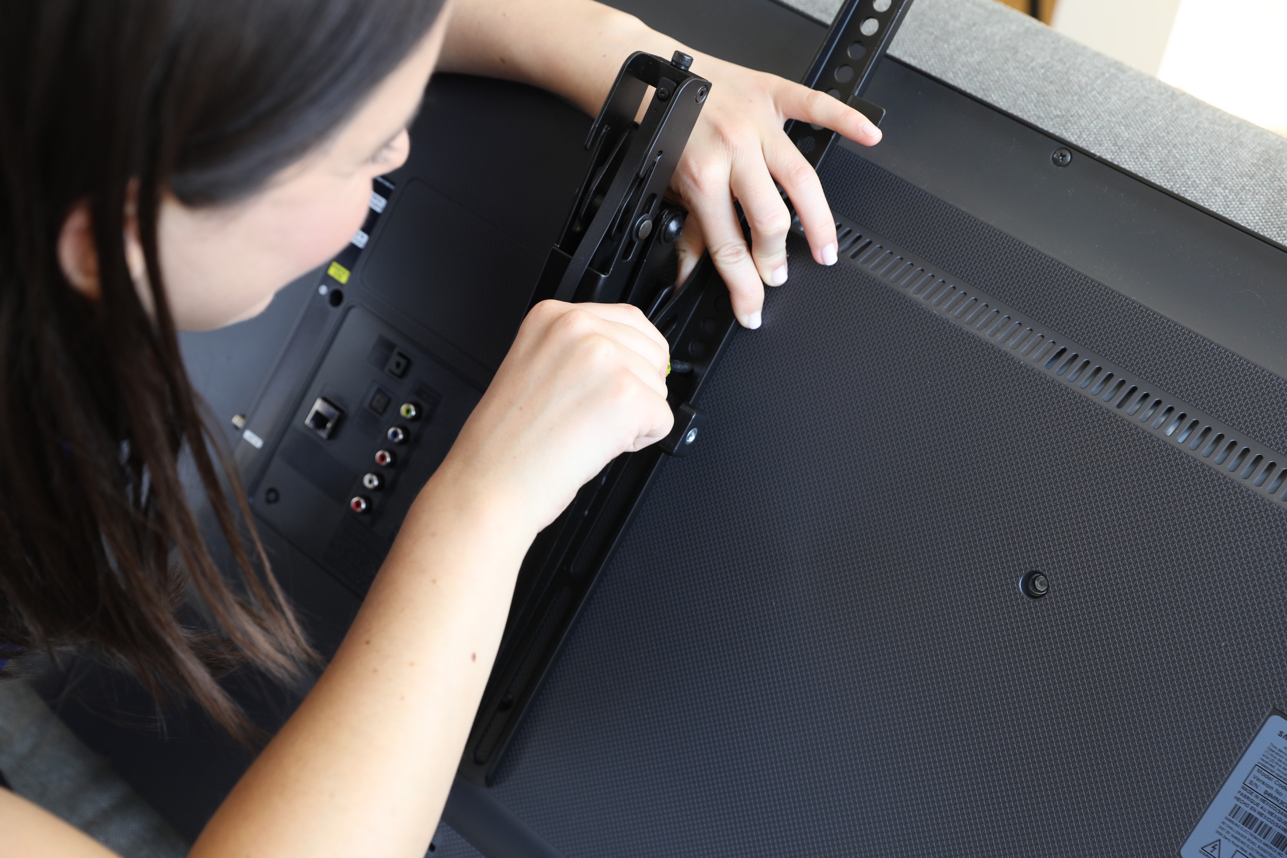 girl attaching mount to back of tv